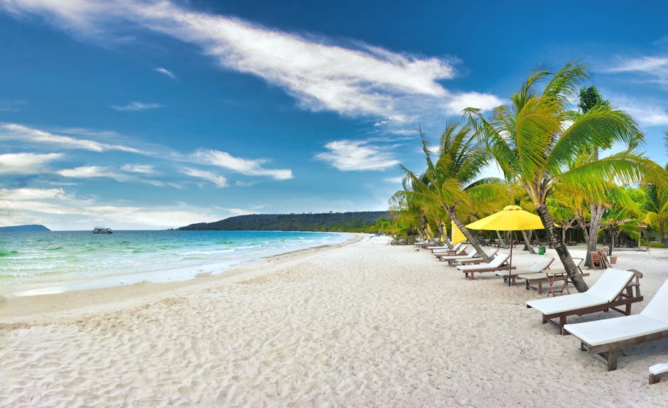 Serene beach scene on Koh Rong, Cambodia with palm trees and lounge chairs.